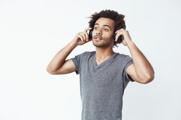 Joven guapo africano escuchando música en auriculares