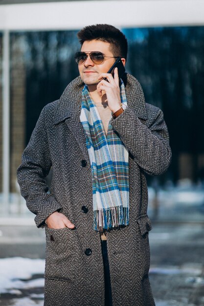 Joven guapo afuera usando el teléfono