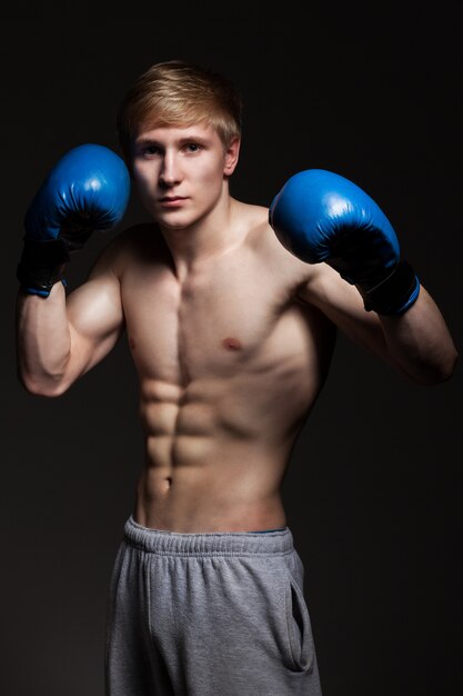 Joven guapo boxeador en guantes azules