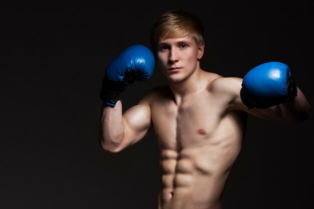 Joven guapo boxeador en guantes azules