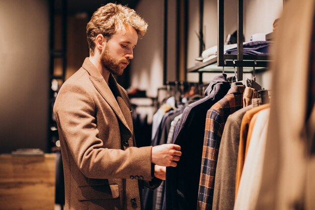 Un joven guapo eligiendo ropa en la tienda.