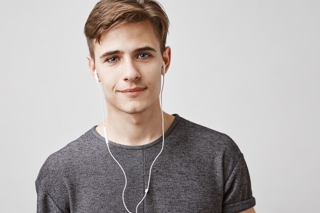 Joven guapo escucha música con auriculares