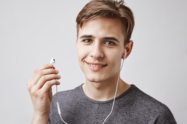 Joven guapo escucha música con auriculares