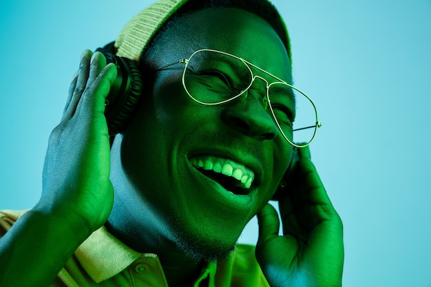 El joven guapo feliz sorprendido hipster hombre escuchando música