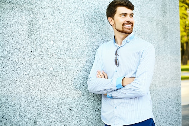 Joven guapo hipster hombre estudiante parado cerca de la pared