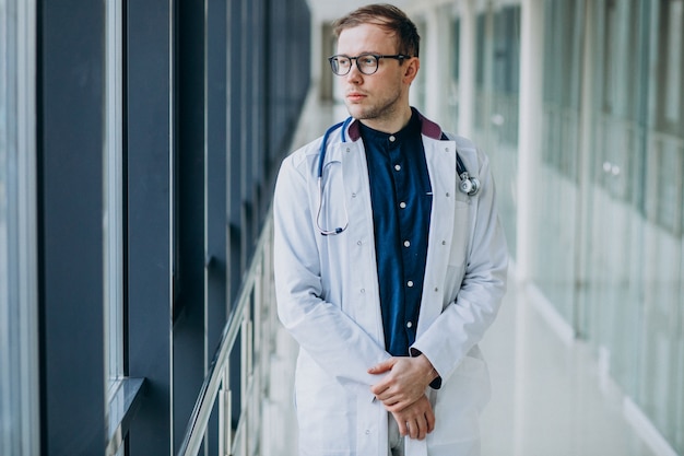 Joven guapo médico con estetoscopio en clínica