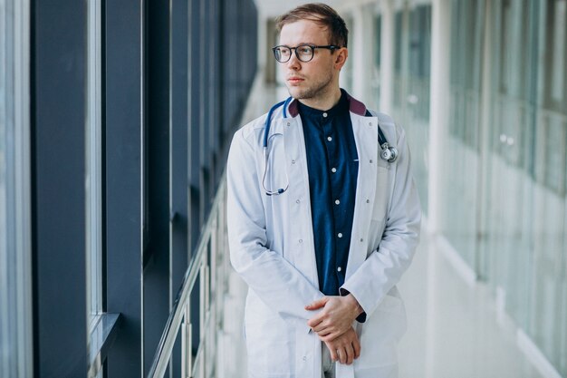 Joven guapo médico con estetoscopio en clínica