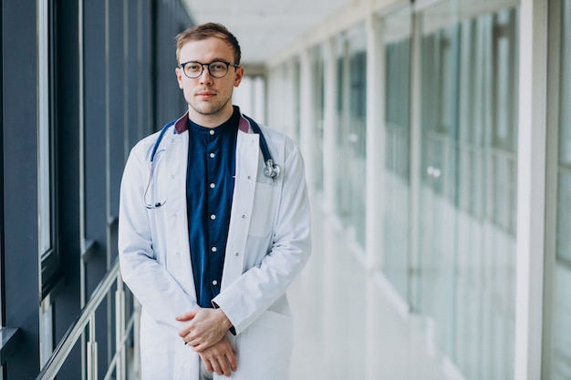 Joven guapo médico con estetoscopio en clínica