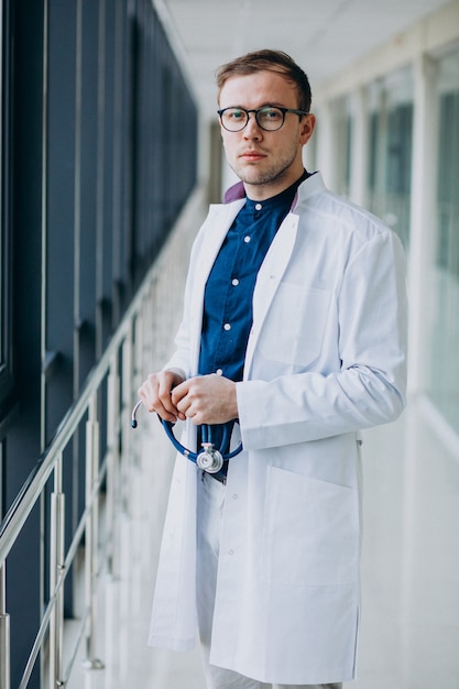 Joven guapo médico con estetoscopio en clínica