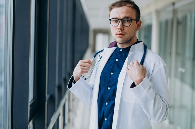 Joven guapo médico con estetoscopio en clínica