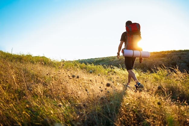 Joven guapo con mochila viajando en el cañón al atardecer