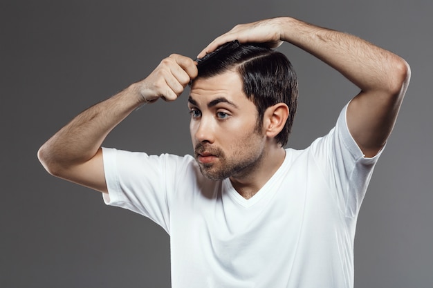 Joven guapo peinando el pelo, corte de pelo