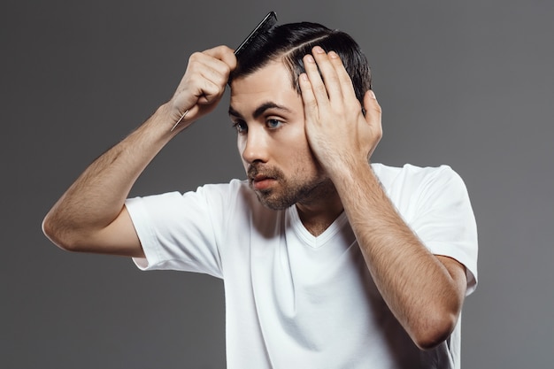 Joven guapo peinando el pelo, corte de pelo