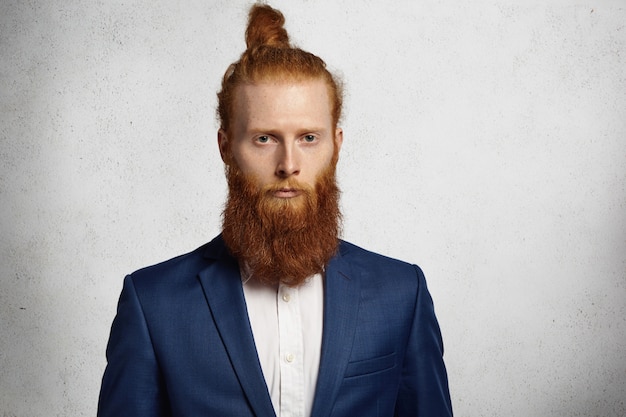 Joven guapo pelirrojo hipster hombre vestido con chaqueta de moda mirando serio y pensativo