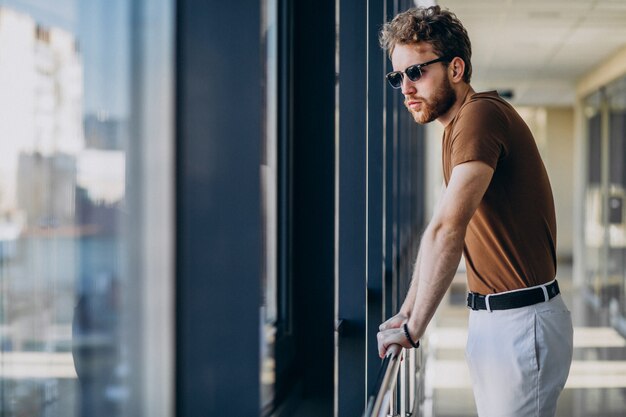 Joven guapo de pie junto a la ventana en el aeropuerto