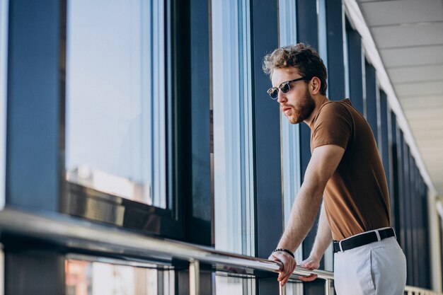 Joven guapo de pie junto a la ventana en el aeropuerto