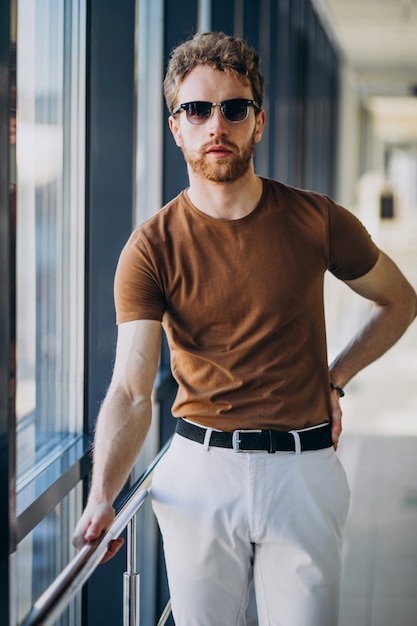 Foto gratuita joven guapo de pie junto a la ventana en el aeropuerto