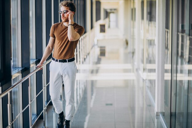 Joven guapo de pie junto a la ventana en el aeropuerto