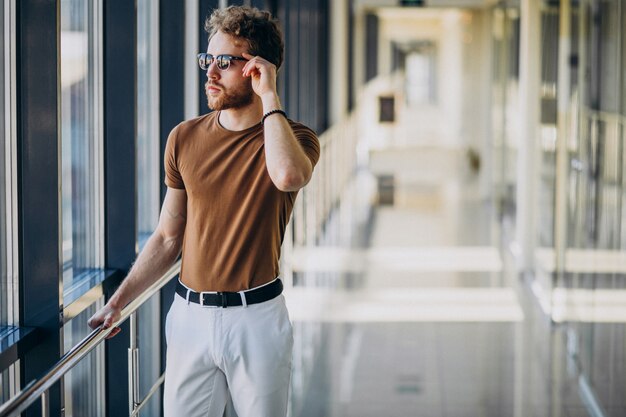 Joven guapo de pie junto a la ventana en el aeropuerto