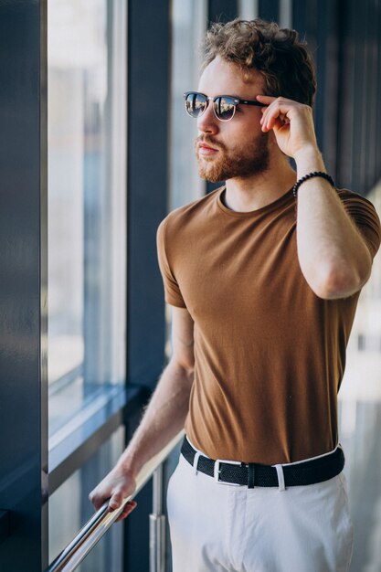 Joven guapo de pie junto a la ventana en el aeropuerto