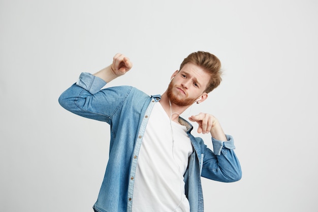 Joven guapo positivo en auriculares escuchando música bailando en movimiento.