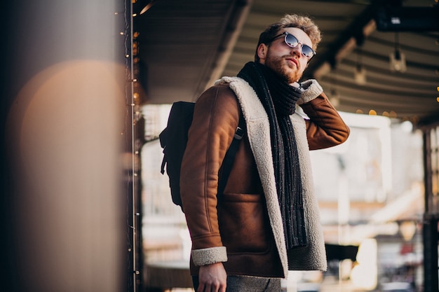 Joven guapo con ropa de invierno caminando en la calle