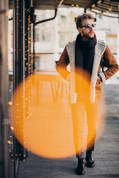 Joven guapo con ropa de invierno caminando en la calle