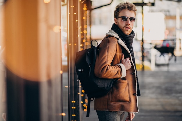 Joven guapo con ropa de invierno y mochila