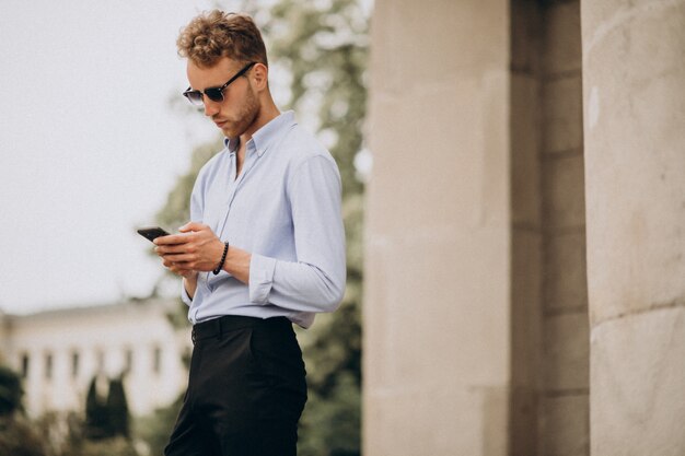 Joven guapo con teléfono en la calle