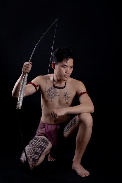 Joven guerrero masculino de Tailandia posando en una posición de combate con un arco