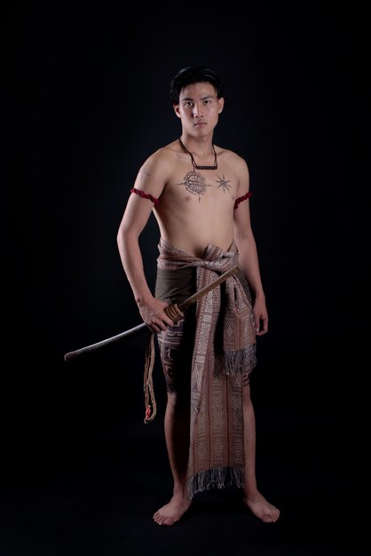 Foto gratuita joven guerrero masculino de tailandia posando en una posición de combate con una espada