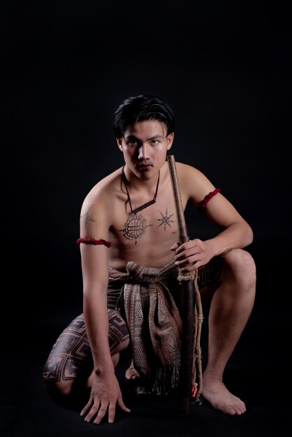 Joven guerrero masculino de Tailandia posando en una posición de combate con una espada