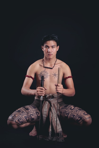 Foto gratuita joven guerrero masculino de tailandia posando en una posición de combate con una espada