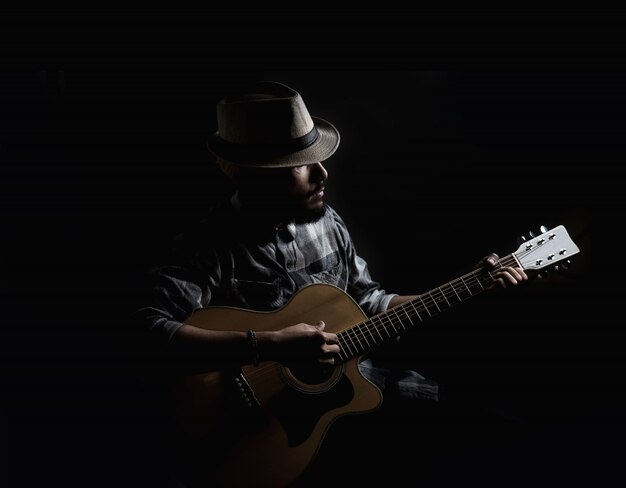 Joven guitarrista hipster jugar en la guitarra acústica.