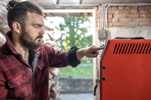 Foto gratuita un joven en una habitación con una caldera de combustible sólido, trabajando en biocombustible, calefacción económica.