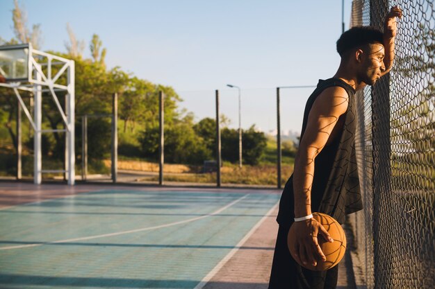 Joven haciendo deporte, jugando baloncesto al amanecer.