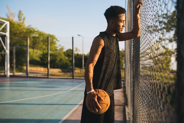 Joven haciendo deporte, jugando baloncesto al amanecer.