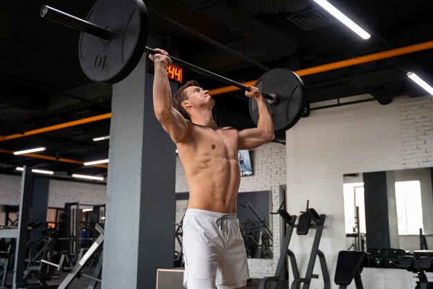 Joven haciendo ejercicio en el gimnasio para culturismo