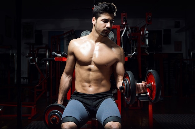 Joven haciendo ejercicio de peso pesado en el gimnasio.