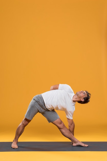 Joven haciendo ejercicios de estiramiento en estera de yoga