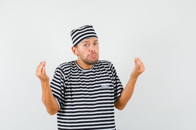 Foto gratuita joven haciendo un gesto italiano disgustado con una pregunta tonta en un sombrero de camiseta a rayas