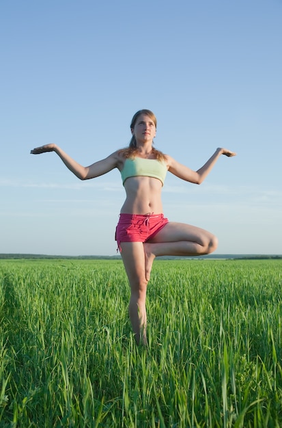 Foto gratuita joven haciendo yoga contra la naturaleza