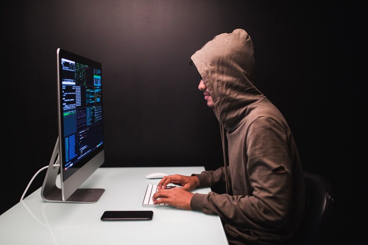 Foto gratuito joven hacker masculino en el cuarto oscuro escribiendo código o usando un programa de virus informático para un ataque cibernético