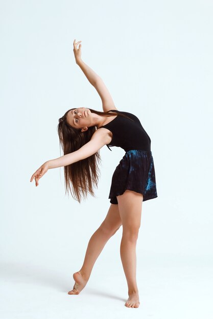 Joven hermosa bailarina contemporánea posando sobre la pared blanca. Copia espacio