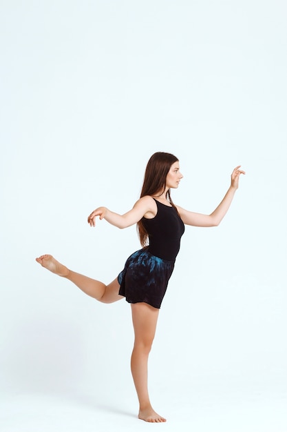 Joven hermosa bailarina contemporánea posando sobre la pared blanca. Copia espacio