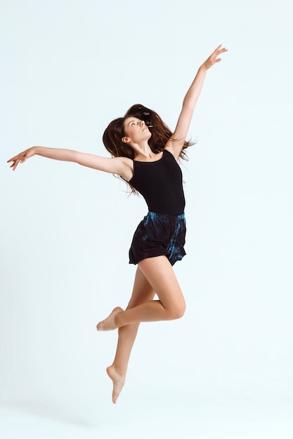 Joven hermosa bailarina contemporánea posando sobre la pared blanca. Copia espacio