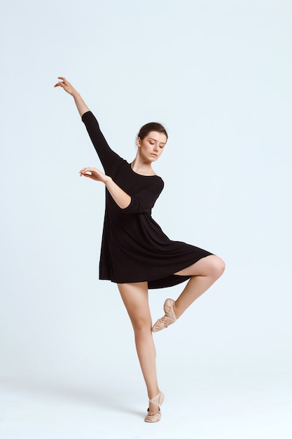 Joven hermosa bailarina contemporánea posando sobre la pared blanca. Copia espacio