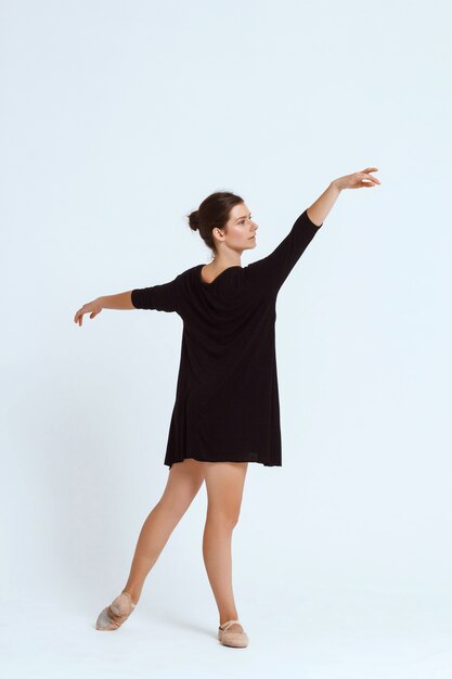 Joven hermosa bailarina contemporánea posando sobre pared blanca