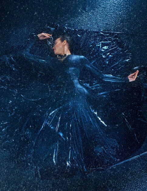 La joven hermosa bailarina moderna bailando bajo las gotas de agua
