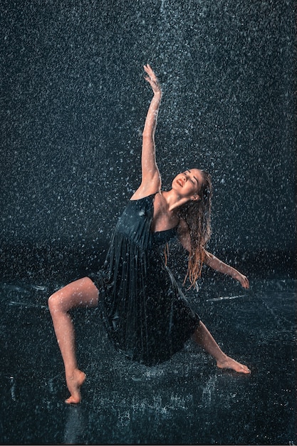 Joven hermosa bailarina moderna bailando bajo gotas de agua